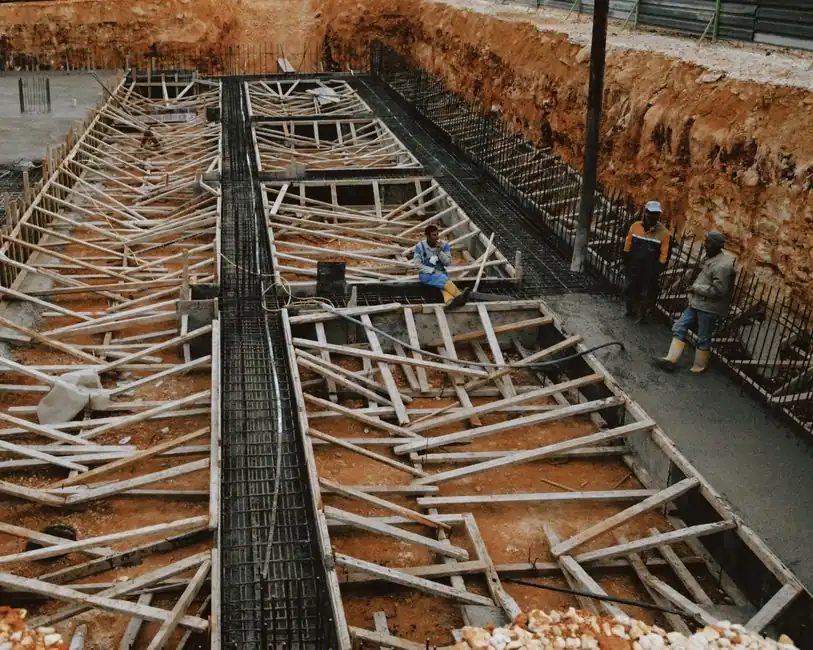 Construction workers at a site with wooden framework in progress, showcasing development.