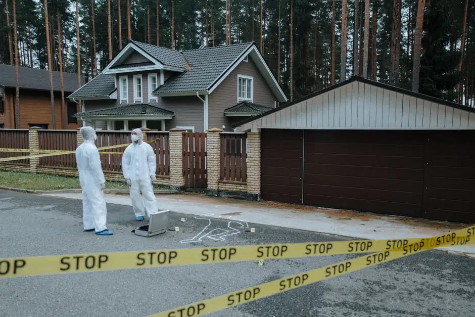 Crime scene investigators in protective suits examining evidence at a suburban house with yellow tape.