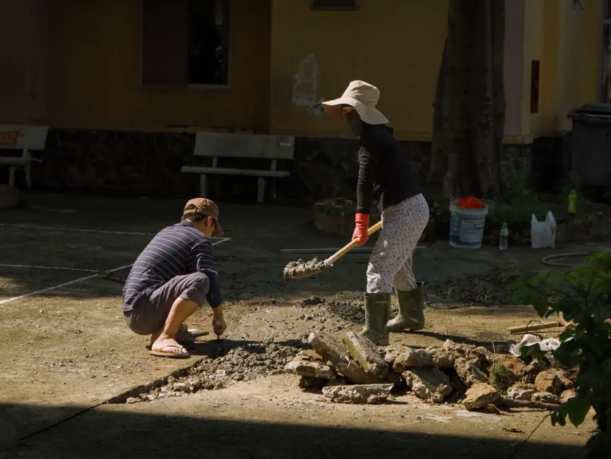 Two people engaged in concrete work outdoors in Hồ Chí Minh City, Vietnam.